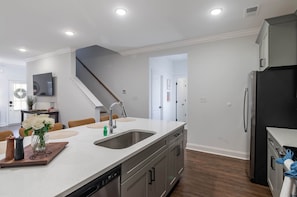 A modern kitchen with a central island, stainless steel appliances, and a wooden floor. - Cottage Grove Haven (Oxford)