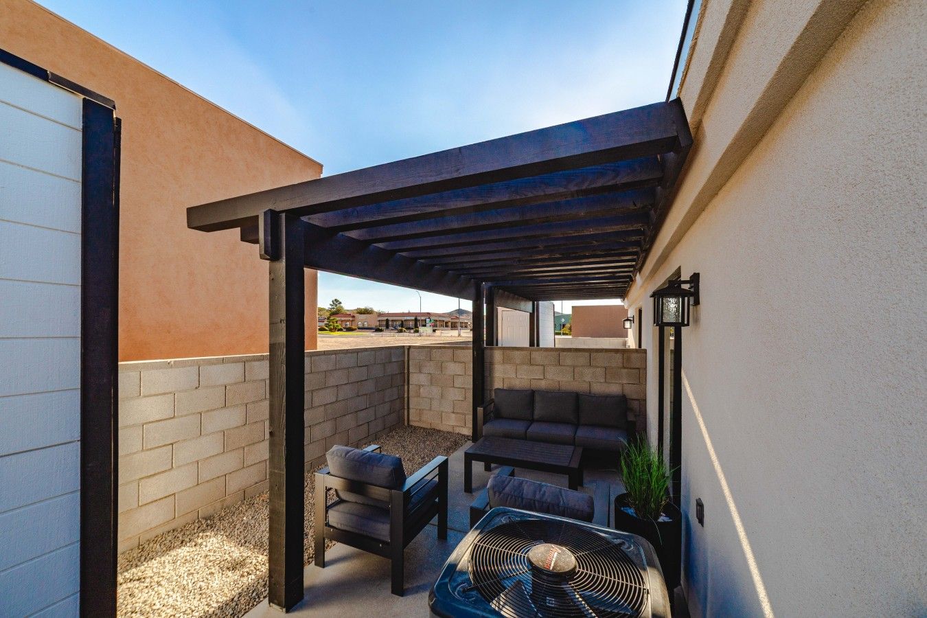 Une terrasse extérieure couverte, équipée d’une table, de chaises et d’un ventilateur.