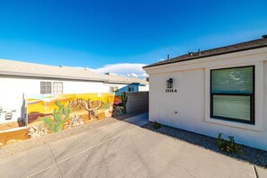 A residential property with a white exterior, a number '1918 A' on the wall, and a mural of desert flora and fauna on the adjacent wall.