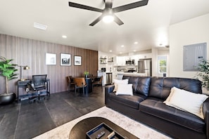 A modern living room with a leather sofa, dining area, and kitchen. - Remote Work Stay with Desk + Private Laundry (Kingman)