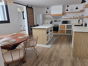 A modern kitchen with a central island, white cabinetry, and wooden accents. - Casa Garnier - a renovated historic home in the city center (Santa Cruz de La Palma)