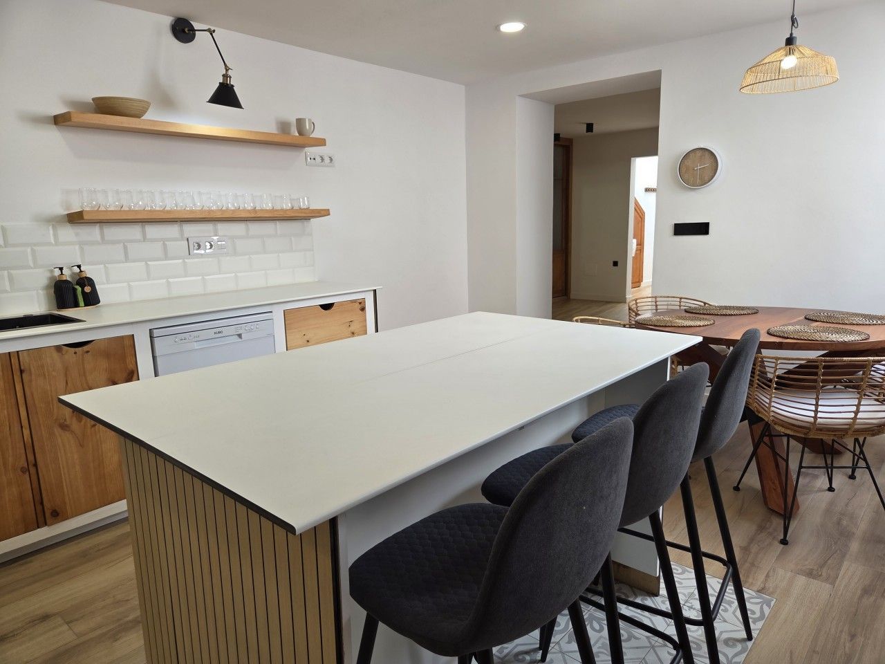 A modern kitchen with a central island, bar stools, and a dining area with a round table.