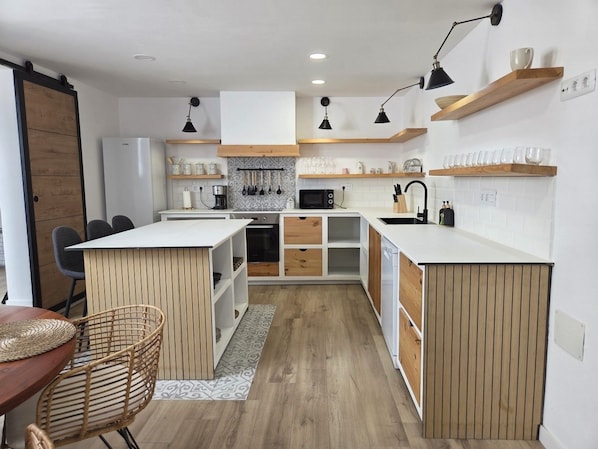 A compact kitchen with white cabinetry, wooden accents, and a central island.