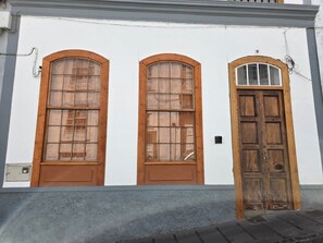 A building facade with three wooden doors and windows, each with a distinct design.