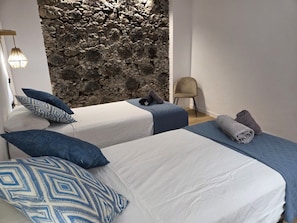 Ein Schlafzimmer mit zwei Betten, einer Steinsäule, einem Sessel und einer Lampe.