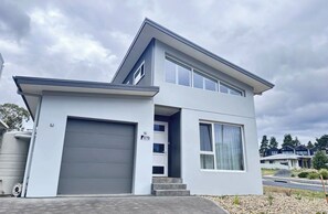 A modern two-story house with a garage, a covered entryway, and a driveway. - Snow and Sun Sanctuary:  East Jindabyne Lakeside escape for Couples or Families. (East Jindabyne)