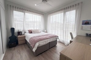 A bedroom with a bed, a guitar, a desk, and curtains. - Snow and Sun Sanctuary:  East Jindabyne Lakeside escape for Couples or Families. (East Jindabyne)