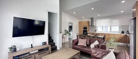 Una sala de estar moderna con un televisor de pantalla plana, una mesa de centro de madera y un sofá de cuero marrón.