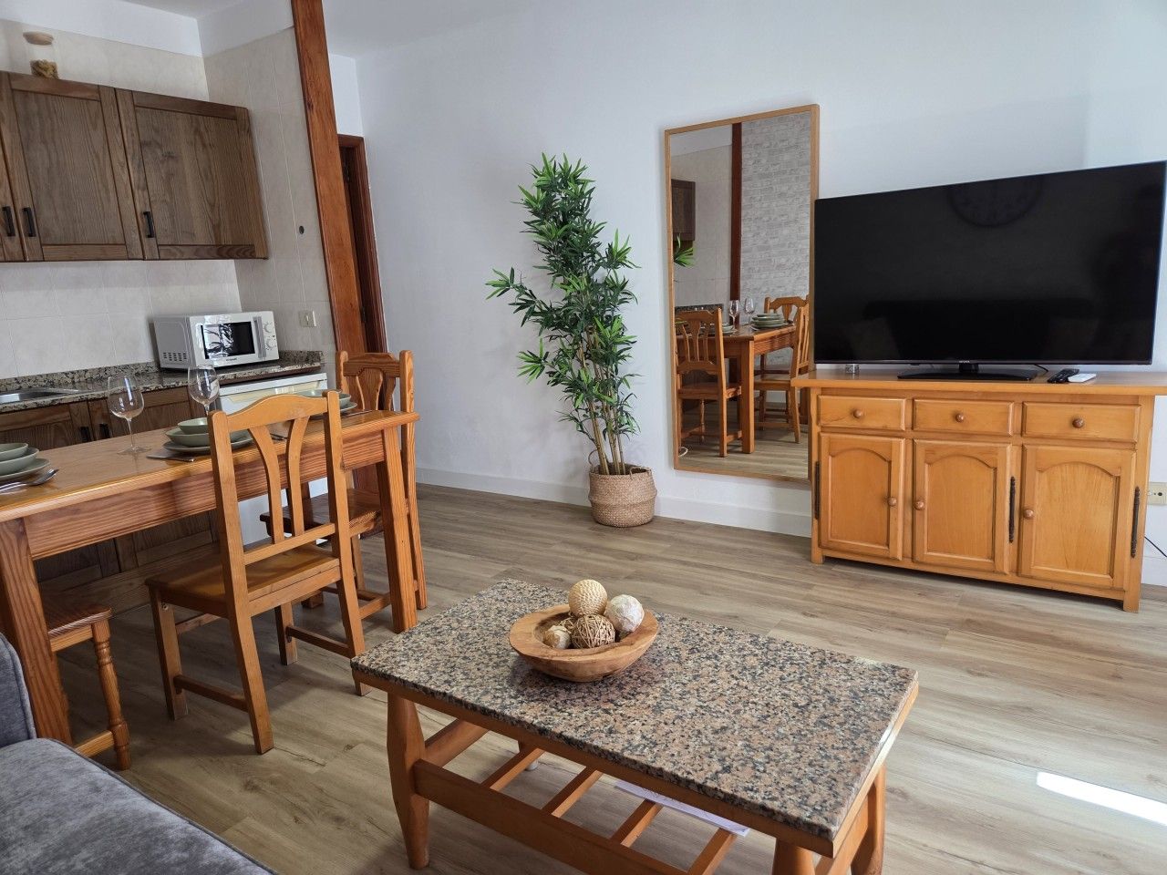 Un salon moderne comprenant un coin repas, des meubles en bois, un téléviseur à écran plat et une plante en pot.