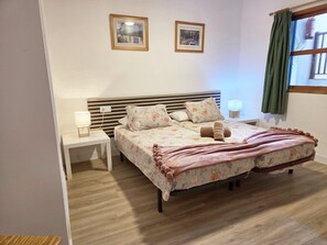 A double bed with floral bedding, a bedside table with a lamp, and two framed pictures on the wall. - Azul, 49 Casa Lago, on the waterfront (Breña Baja)