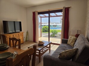 A living room with a television, dining table, and sofa. - Azul, 49 Casa Lago, on the waterfront (Breña Baja)