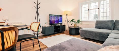 Una sala de estar moderna con un sofá, una mesa de comedor con sillas, un televisor y una lámpara.