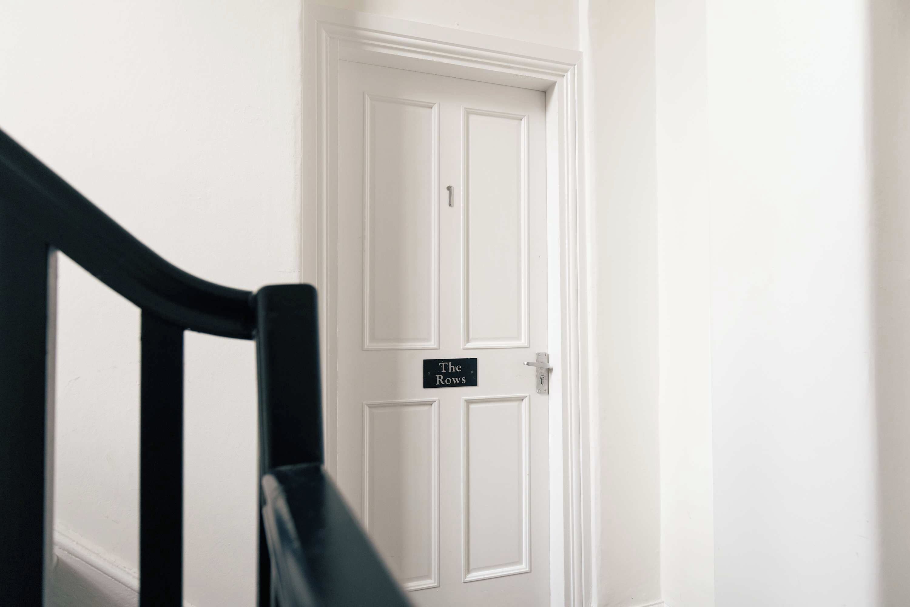 Une porte blanche avec une pancarte indiquant : « The Rows ».