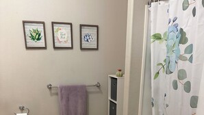 A bathroom with a toilet, sink, towel rack, shower curtain, and framed wall art. - Red Rock Retreat- Spacious Yard + RV Parking (Ivins)