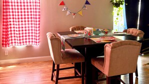 A dining area with a table set for four, a ceiling fan, and a window with curtains. - Red Rock Retreat- Spacious Yard + RV Parking (Ivins)