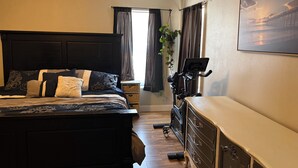A bedroom with a bed, a desk, a chair, a treadmill, and a window with curtains. - Red Rock Retreat- Spacious Yard + RV Parking (Ivins)