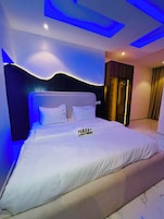 Un dormitorio moderno con una cama grande, cabecera con iluminación integrada y un armario visible.