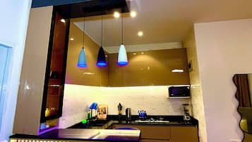 Una cocina moderna con iluminación colgante, microondas y estufa.