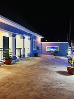 Un edificio con una marquesina, plantas en macetas y una pantalla iluminada grande.