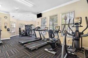 Une salle de sport équipée de tapis de course, de vélos elliptiques et de matériel de musculation.