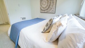 A bedroom with a bed, a blue blanket, patterned pillows, a wall art piece, and a window. - Eastlake Guest Suite near SLU with Private Patio (Seattle)