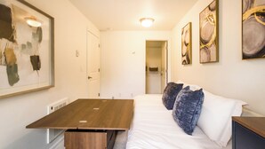 A hotel room with a bed, a wooden table, a bench, and artwork on the walls. - Eastlake Guest Suite near SLU with Private Patio (Seattle)