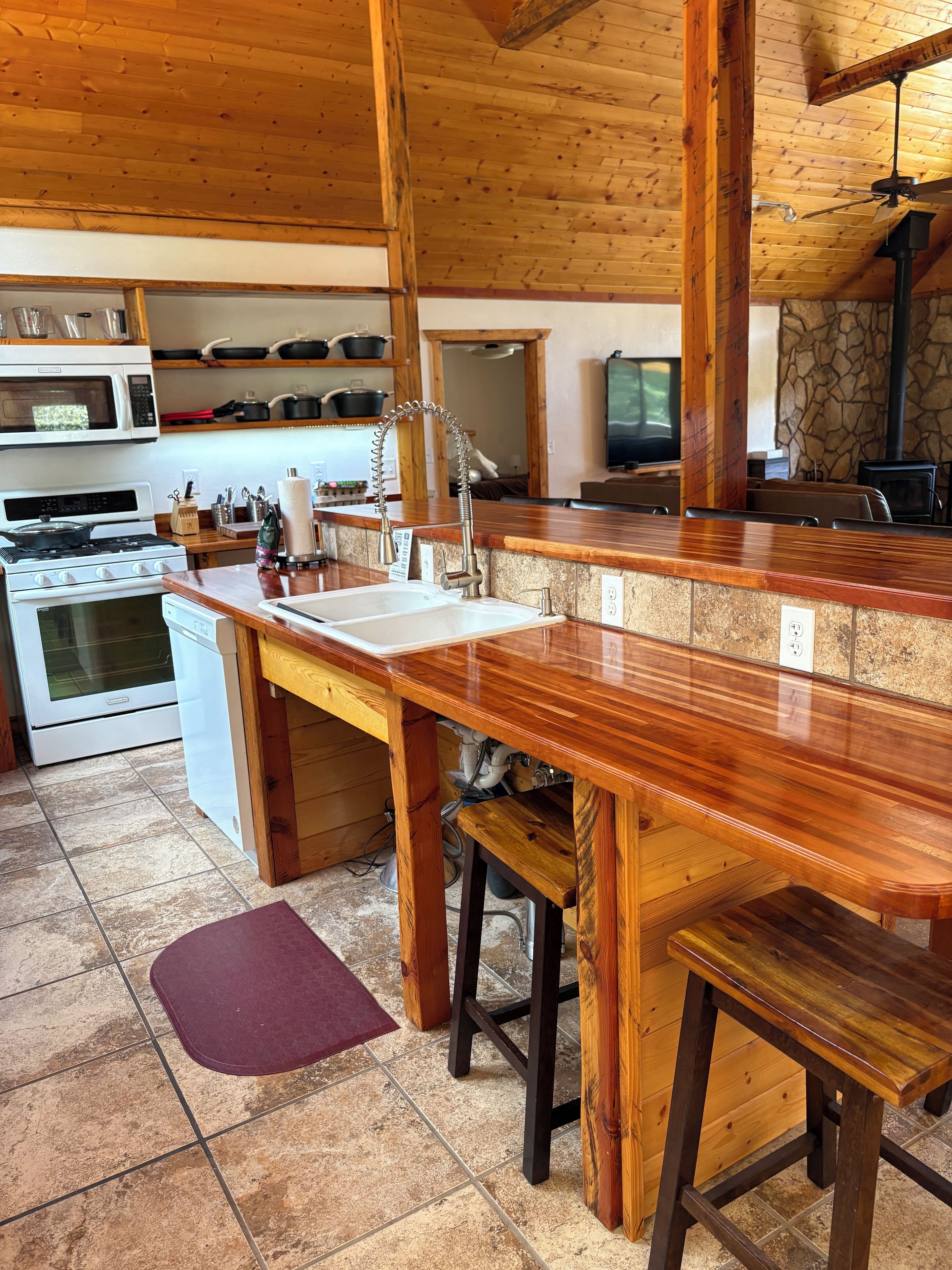 A kitchen with wooden countertops, a sink, and a stove.