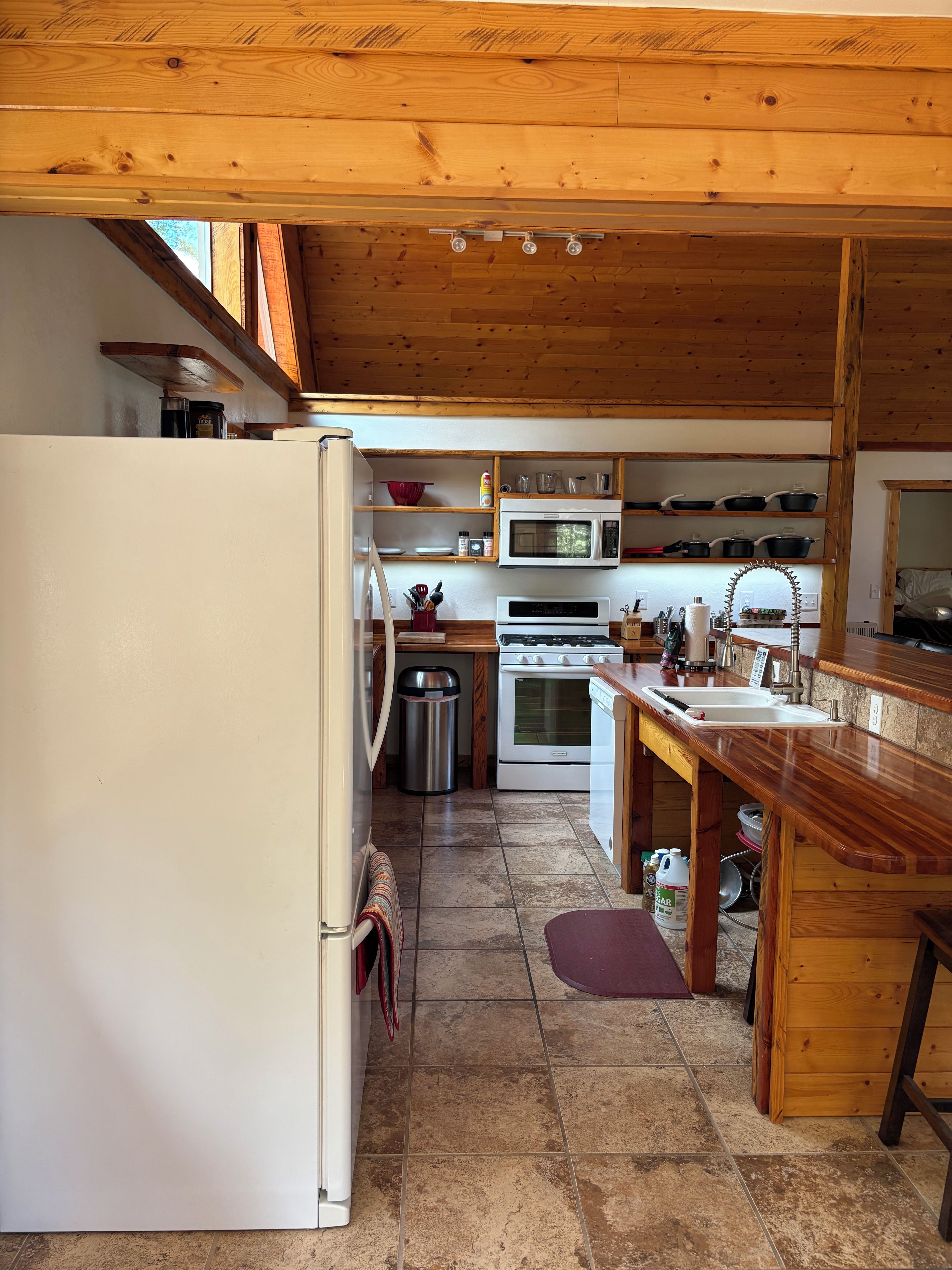 Una cucina con travi in legno, un frigorifero, fornello, forno a microonde e lavello.