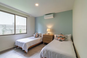 A bedroom with two beds, a nightstand, a lamp, and a window. - Vrbo Property (Cuernavaca)