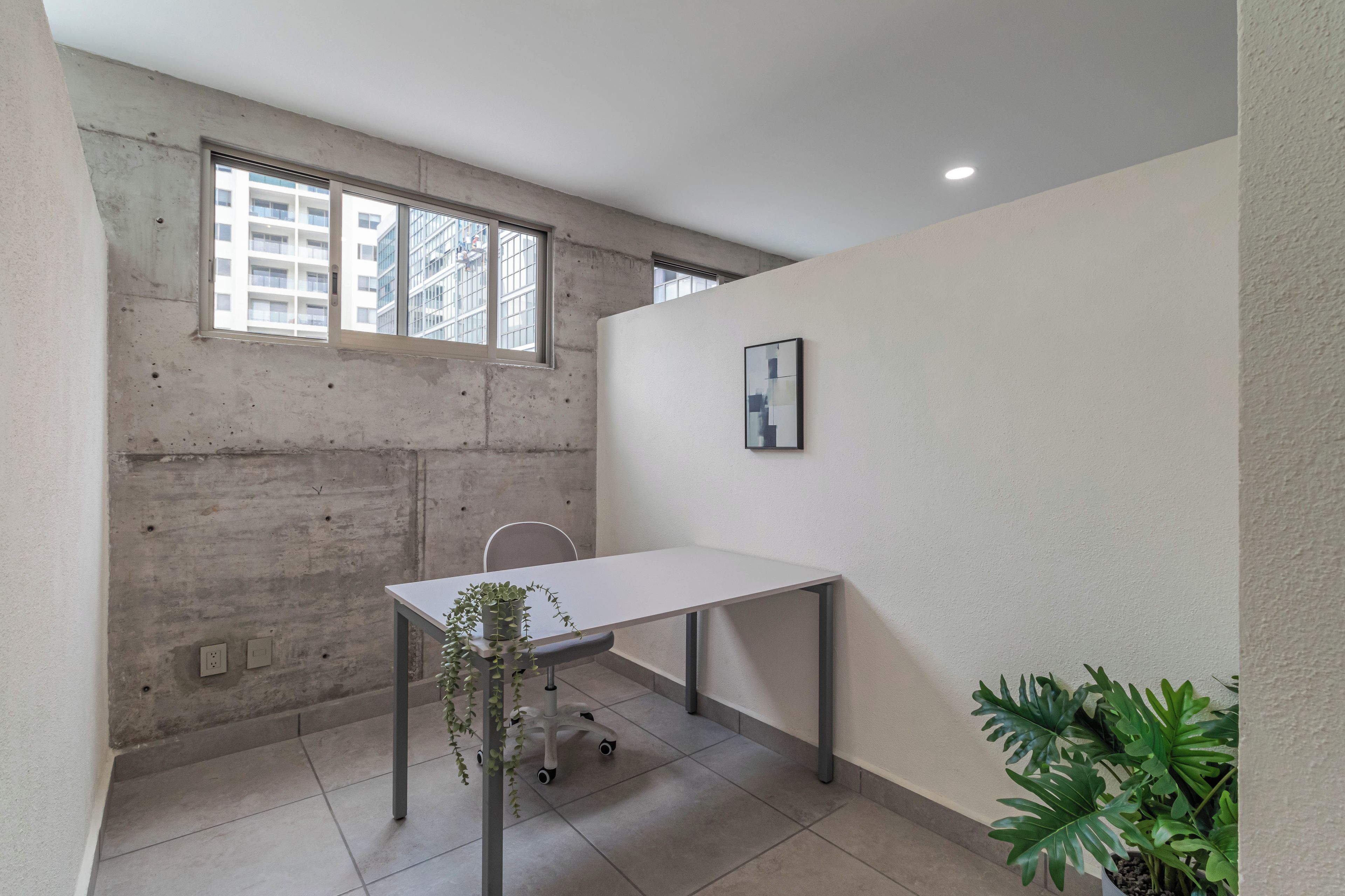 A room with a white table, a potted plant, and a framed picture on the wall.