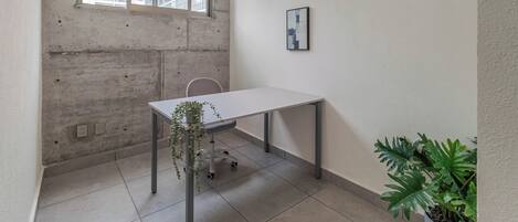 A room with a white table, a potted plant, and a framed picture on the wall.