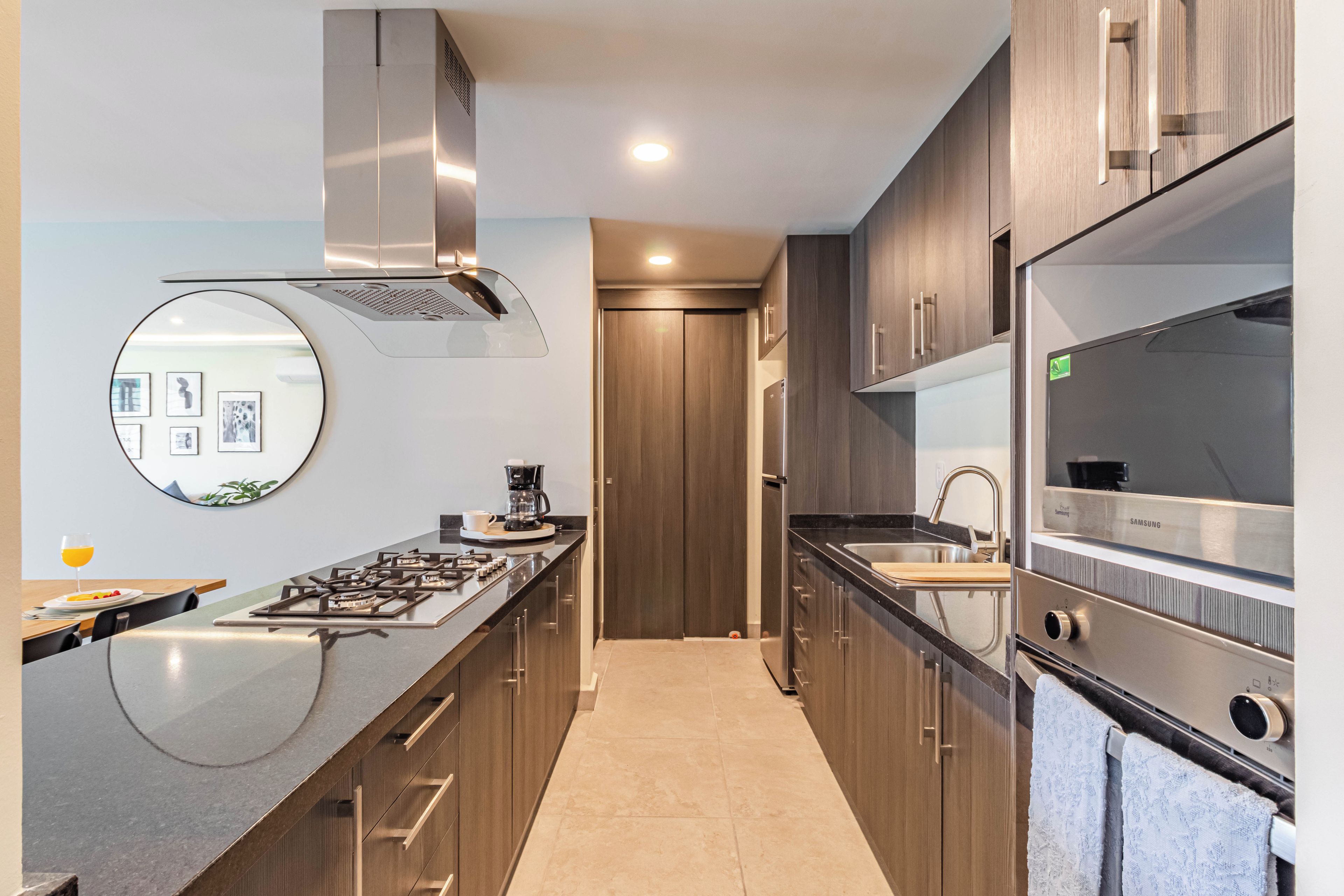 A modern kitchen with a central island, stainless steel appliances, and wooden cabinetry.