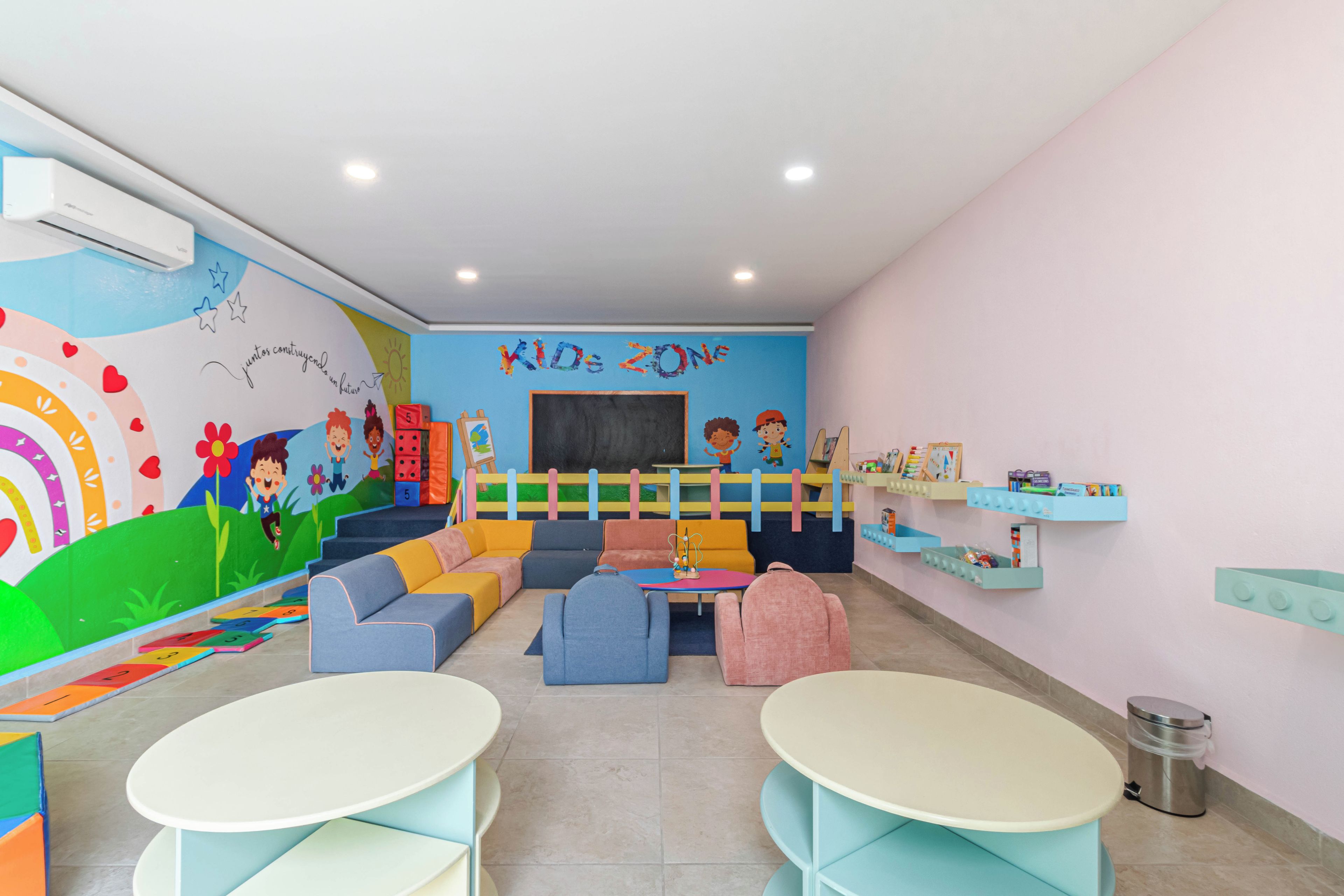 Une salle de jeux pour enfants avec des meubles aux couleurs vives, une fresque murale et des jouets éducatifs.