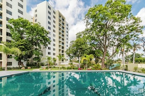 A swimming pool with clear water, surrounded by lush greenery and modern buildings. - Vrbo Property (Cuernavaca)