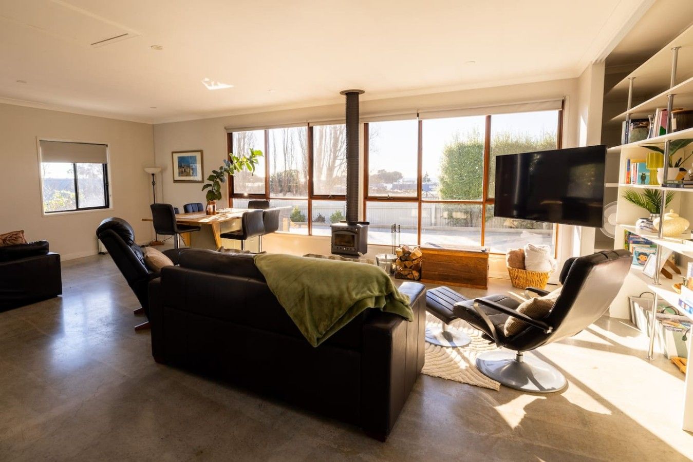 A modern living room with a sofa, a recliner, a TV, and a fireplace.