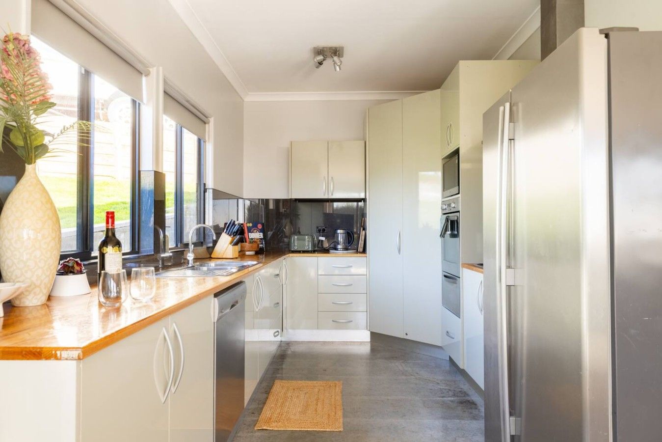 Eine moderne Küche mit weißen Schränken, Edelstahlgeräten und einer Holz Arbeitsplatte.