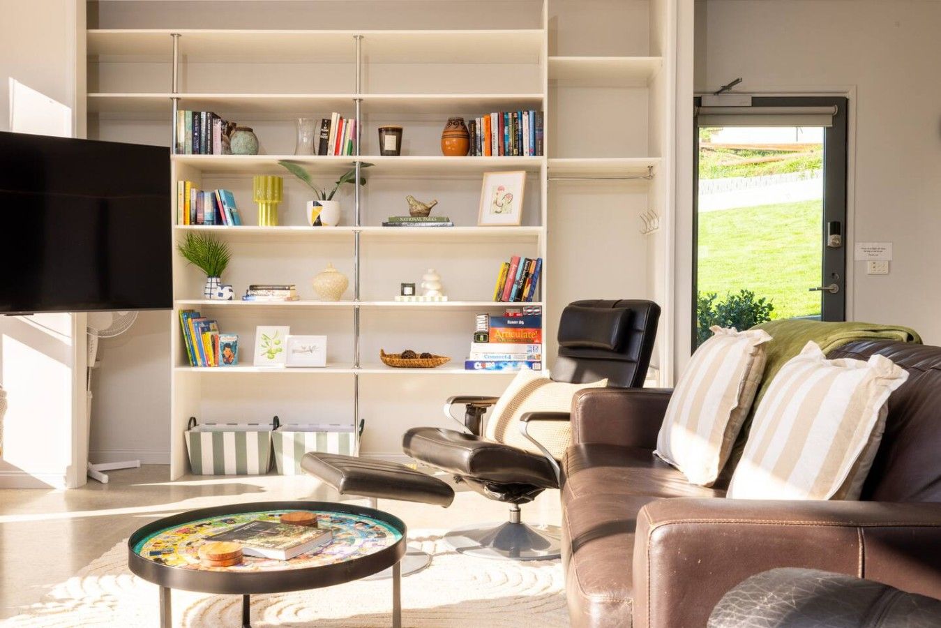 Un salon comprenant un canapé, une table basse, une bibliothèque et un téléviseur.