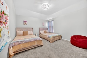 A bedroom with two beds, a red bean bag, and a ceiling light fixture. - *NEW* 6BR, 4 Kings, MovieRoom, BilliardS, MiniGolf (Katy)