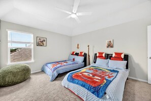 Een slaapkamer met twee bedden, een plafondventilator en een raam met jaloezieën.