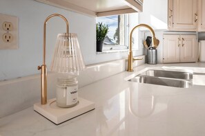 Een moderne keuken met een wit aanrechtblad, een roestvrijstalen spoelbak en een goudkleurige kraan.