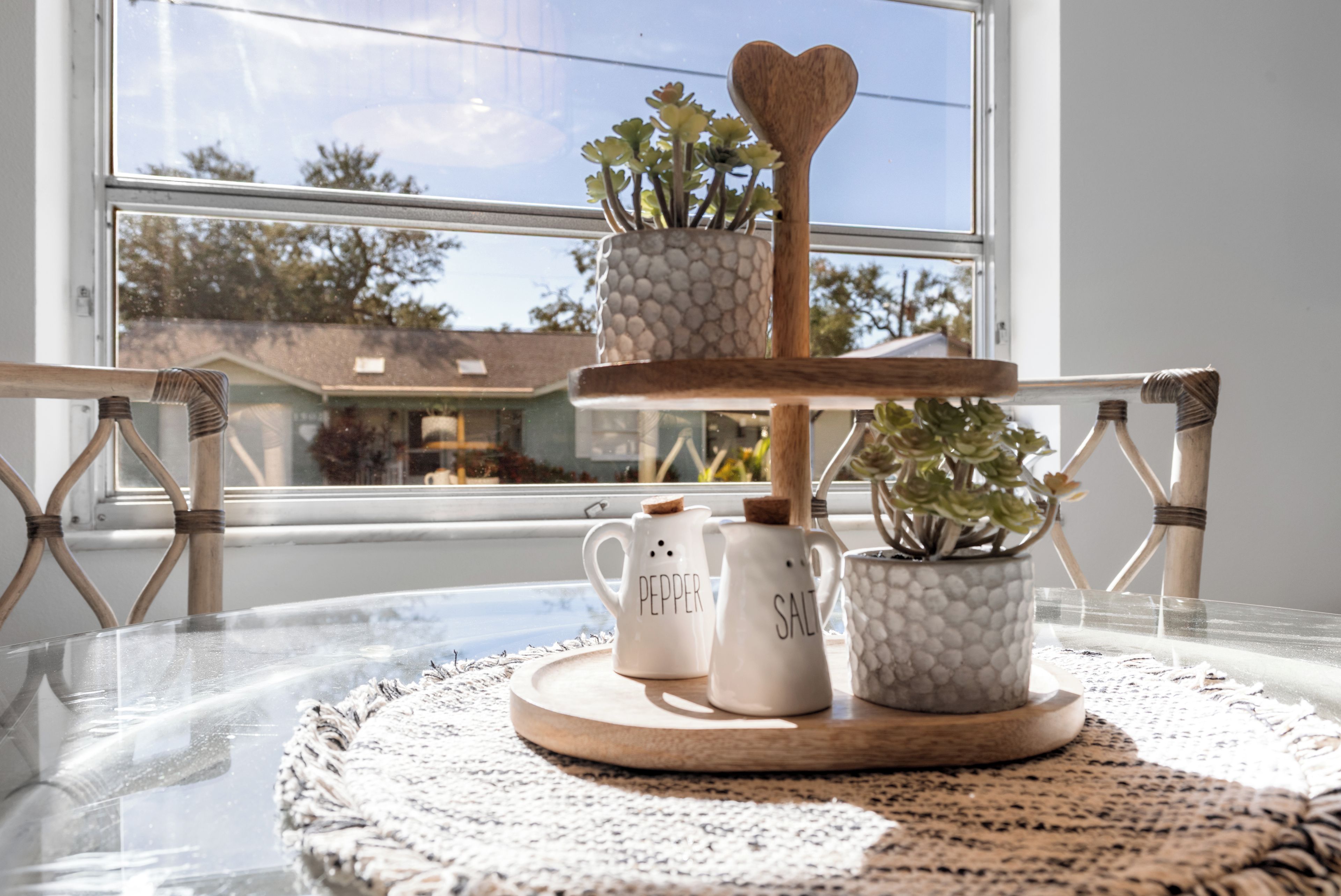 A table with a tray holding two white ceramic mugs, one labeled 'PEPPER' and the other 'SALT,' and a small potted plant.