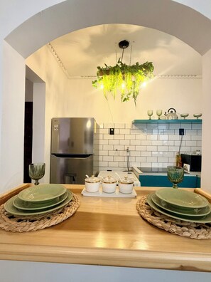 Ett kök med modern design, med bland annat ett kylskåp i rostfritt stål, en hängande växtlampa och en kakelbeklädd vägg bakom diskbänken.
