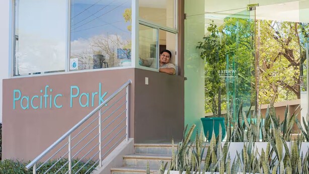 Entrada de un edificio con una escalera, un cartel que dice 'Pacific Park' y un puerta de vidrio.