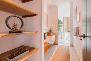 A hallway with wooden shelves, a small statue, and a view into a bathroom with a bathtub. - Reserve Costa Rica - 3 Bed - ocean view condo Tamarindo (Tamarindo)