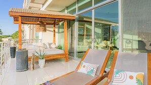Un espacio lounge moderno al aire libre con una pérgola de madera, un sofá y sillones.