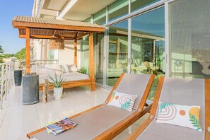 A modern outdoor lounge area with a wooden pergola, a sofa, and lounge chairs. - Ideally situated in the heart of town and a 4 min walk to the Beach. (Tamarindo)