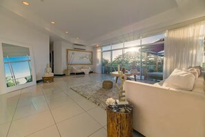 A spacious living room with a large window, a white sofa, and a wooden coffee table. - Ideally situated in the heart of town and a 4 min walk to the Beach. (Tamarindo)