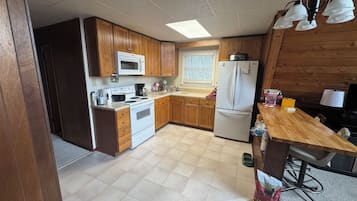 Une cuisine compacte avec des meubles de rangement en bois, un réfrigérateur blanc, un four à micro-ondes et une cuisinière.