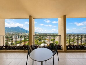 A balcony with a round table and two chairs, overlooking a cityscape with mountains and buildings. - Vrbo Property (San Salvador)