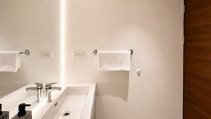 Une salle de bain moderne avec un grand miroir, deux lavabos et une porte en bois.